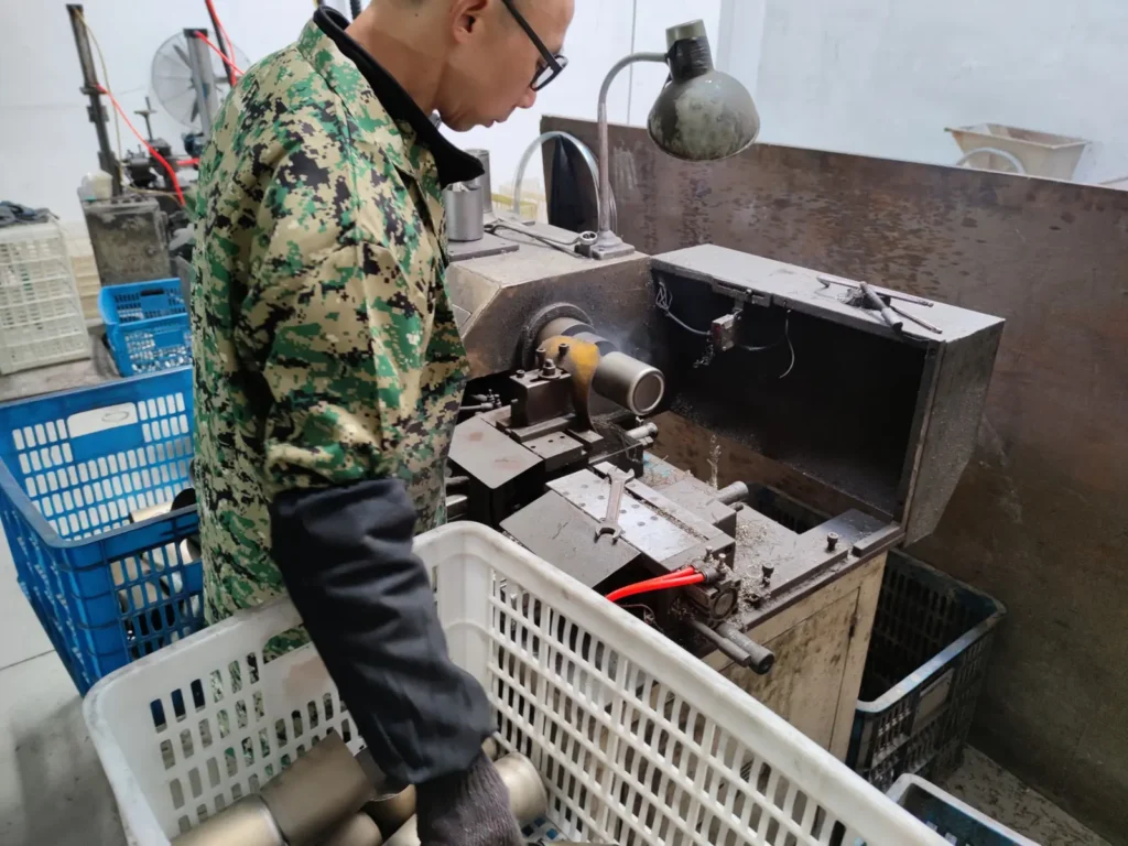 Worker trimming the rim of a stainless steel mug